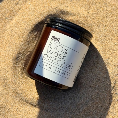 Świeca z wosku pszczelego 250 g MiUT ustawiona na piasku w naturalnym świetle, produkt ekologiczny