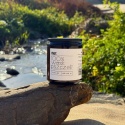 Świeca z wosku pszczelego 250 g MiUT ustawiona na skale przy rzece, w otoczeniu zieleni, produkt naturalny