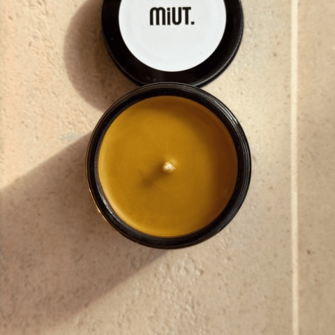 Świeca z wosku pszczelego 60 g MiUT w szklanym słoiku ustawiona na jasnym tle, naturalny produkt handmade